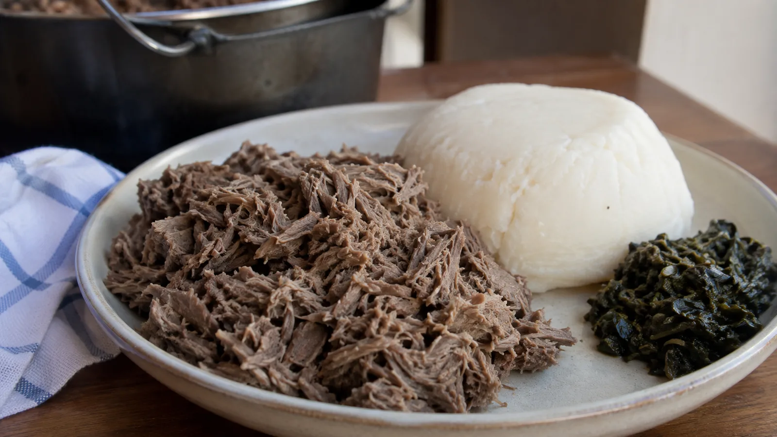 Pounded Botswana beef seswaa served with firm white pap and a small portion of cooked greens.